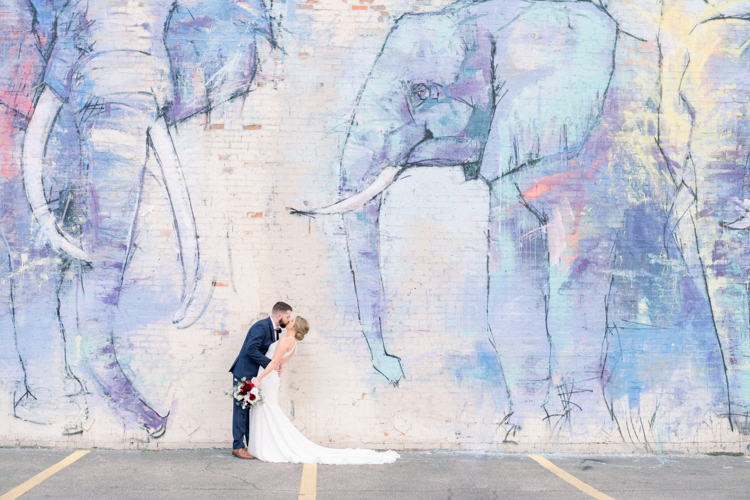 bride and groom kissing in front of elephant mural in Dallas